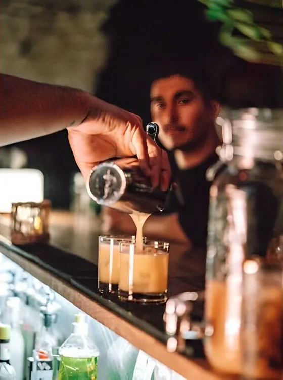 Un cocktail versé au shaker derrière le bar